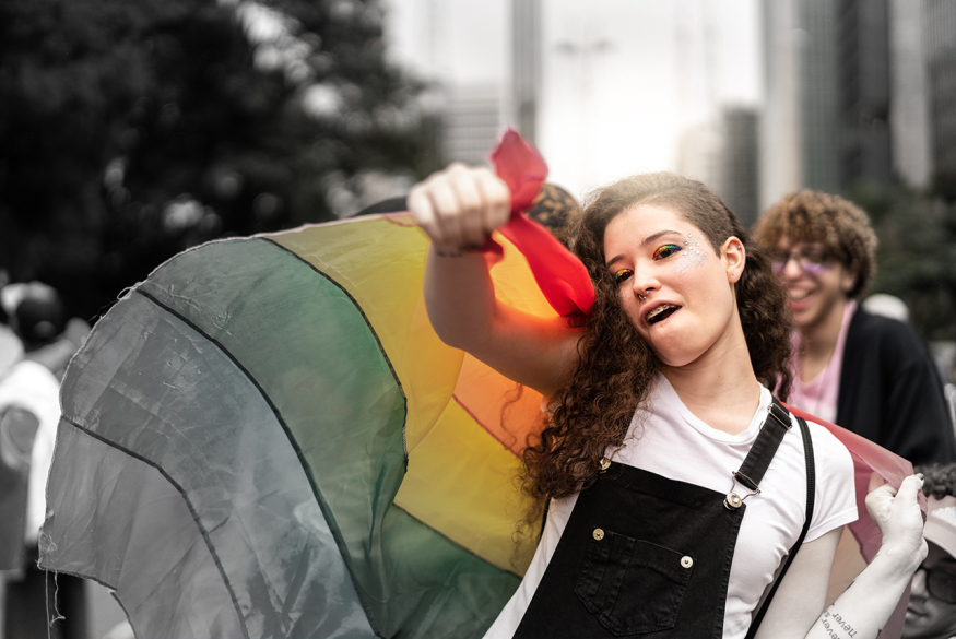 meisje houdt regenboogvlag vast en steekt vuist in de lucht