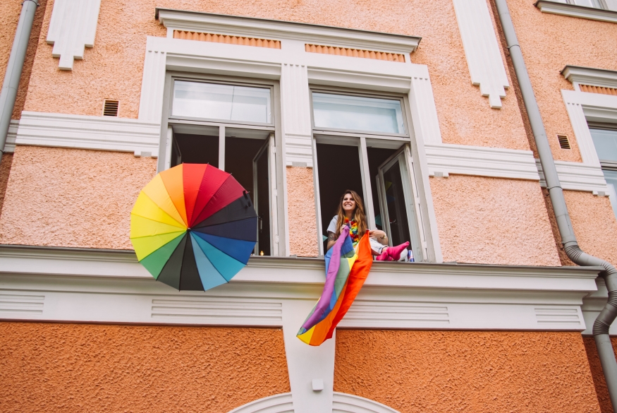 person in window with rainbow flag