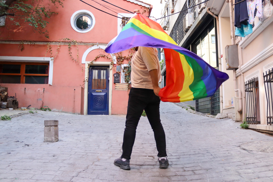 Persoon met regenboogvlag in de straat