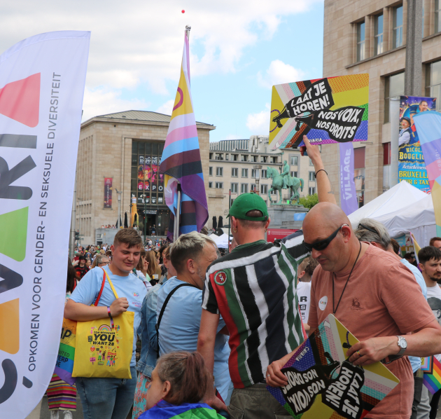 Groep personen op Pride, met bannervlag van çavaria en bord met 'laat je horen'
