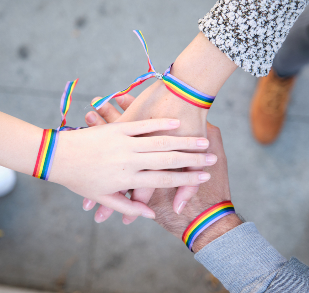 3 handen op elkaar met regenboogbandje