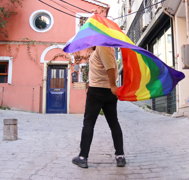 Persoon met regenboogvlag in de straat