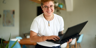 Persoon met witte t-shirt staat recht en heeft laptop vast