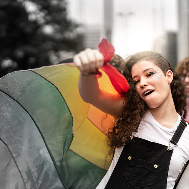 meisje houdt regenboogvlag vast en steekt vuist in de lucht