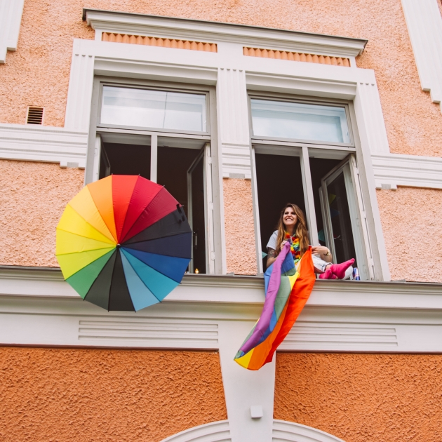 person in window with rainbow flag