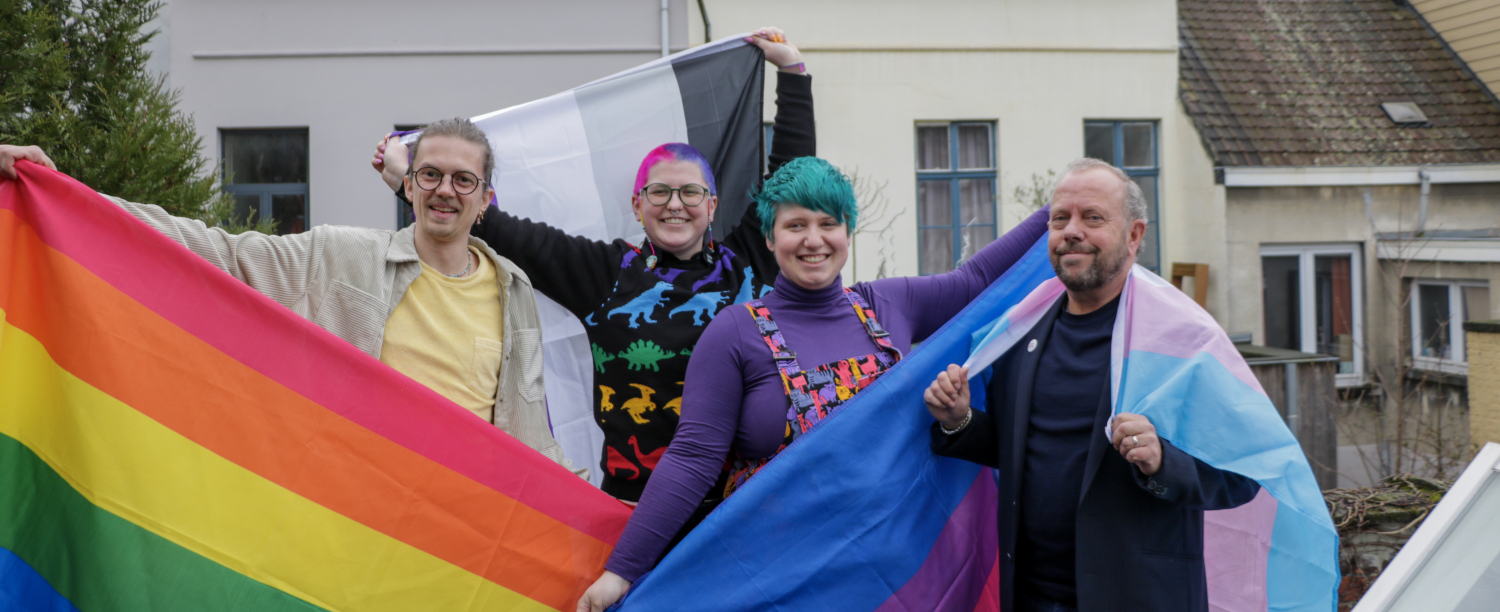 Vier personen met pridevlaggen (een regenboogvlag, een asexual vlag, een bi vlag en een trans vlag)