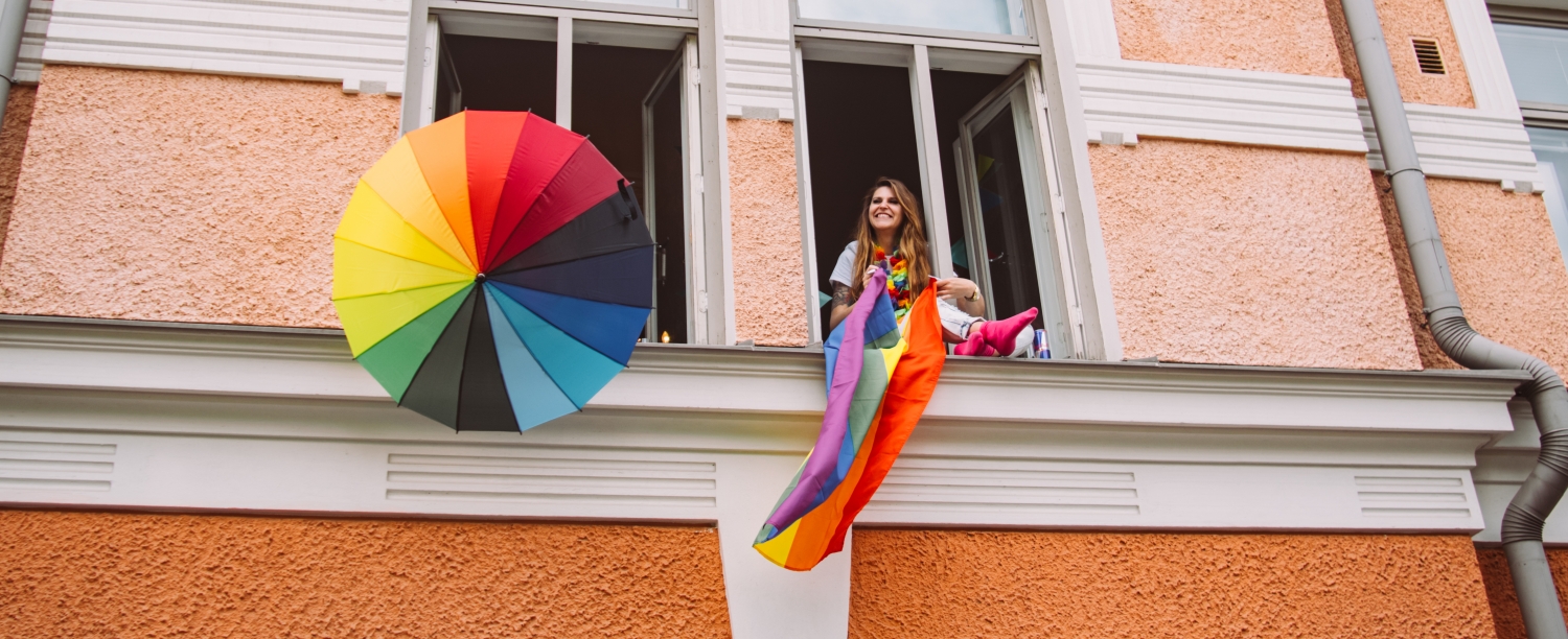 person in window with rainbow flag