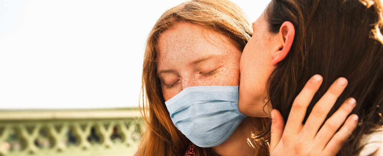 Vrouw met mondmasker wordt gekust.