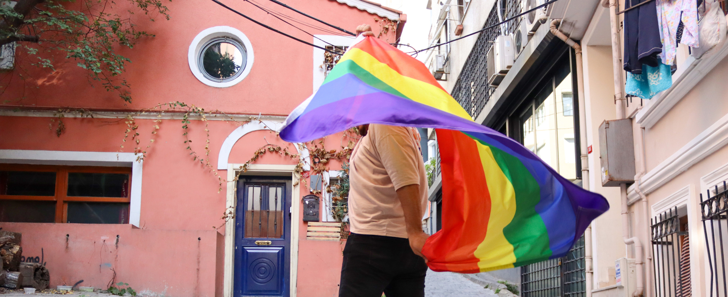 Persoon met regenboogvlag in de straat