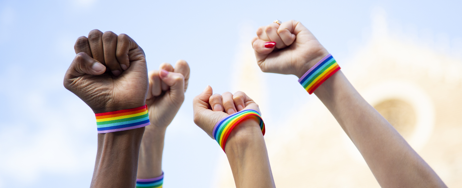 Vier vuisten in de lucht met regenboogarmbandjes Vier vuisten in de lucht met regenboogarmbandjes