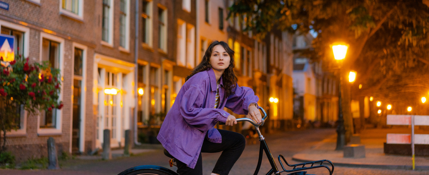 Leerling op de fiets in de stad in de schemering